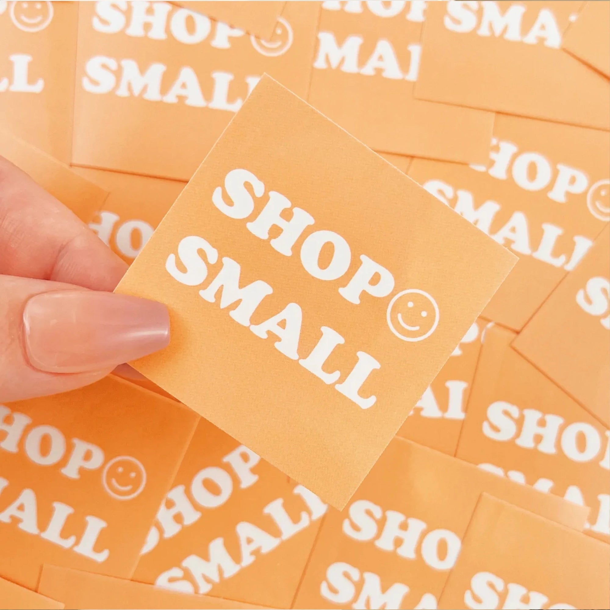 Custom orange square sticker displaying &quot;SHOP SMALL&quot; with a smiling face, emphasizing support for local businesses.