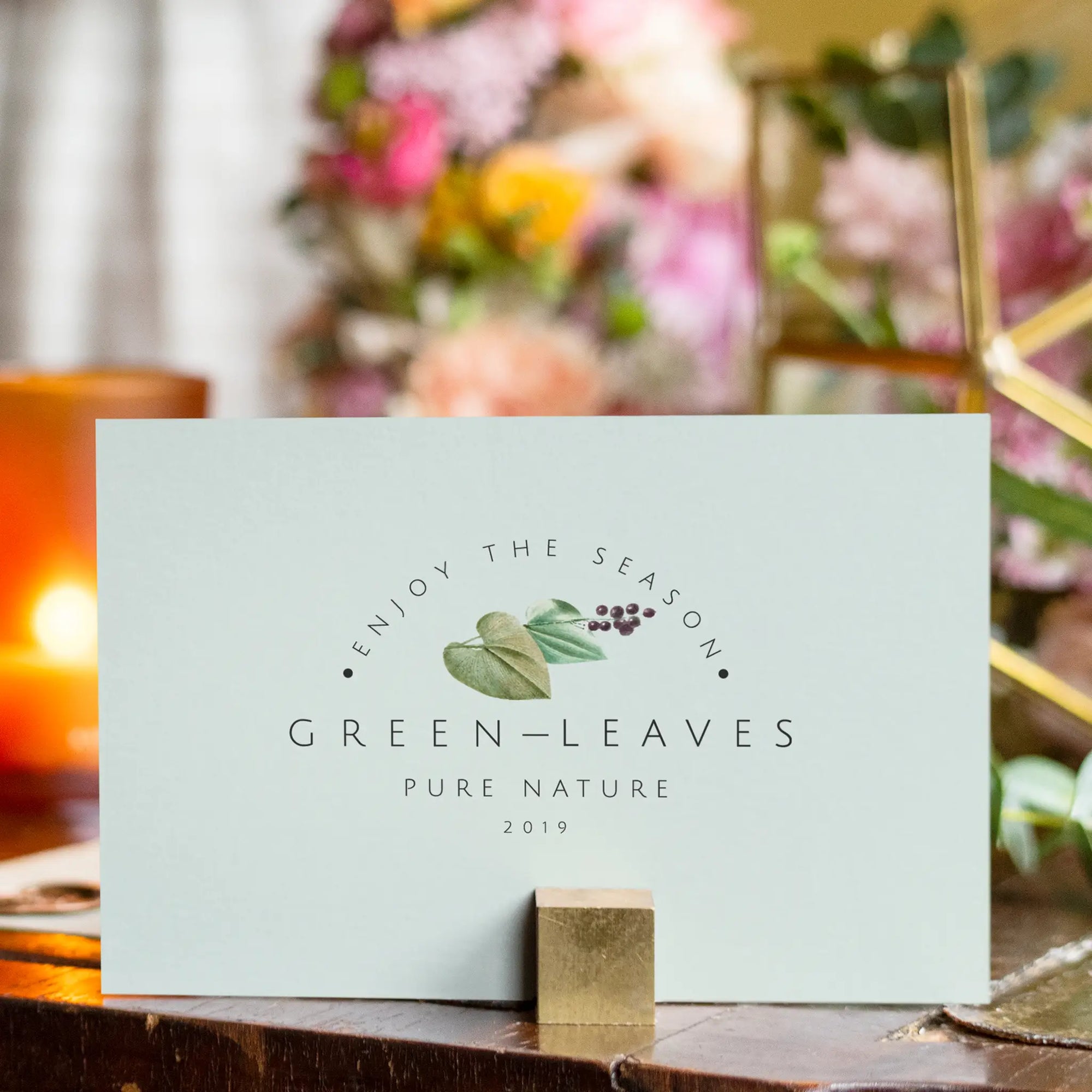 Custom card with 'Enjoy the Season' design, featuring greenery and elegant branding in a floral setting.