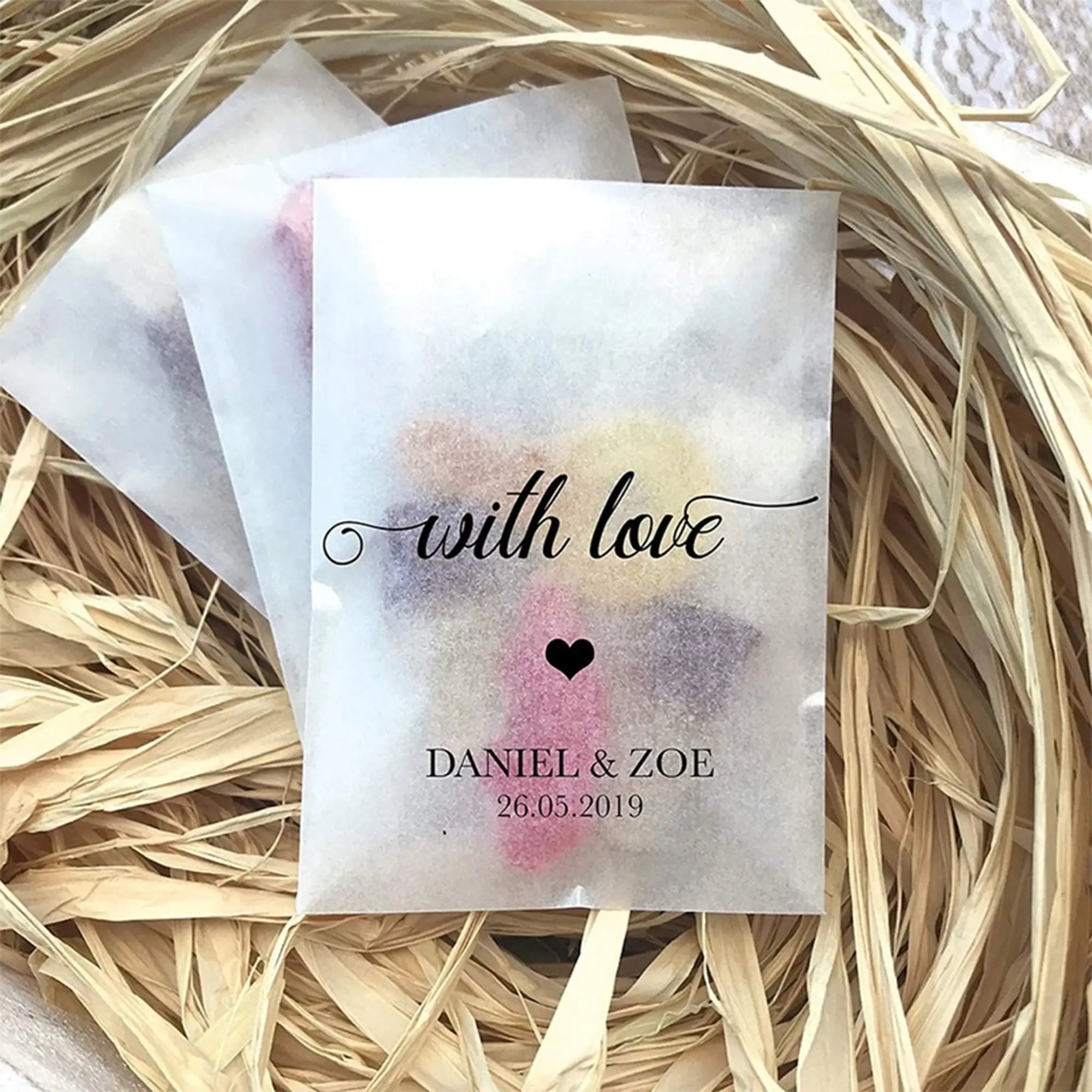 Custom glassine bags with printed design &quot;with love&quot; and names &quot;Daniel &amp; Zoe,&quot; set in natural straw decor.