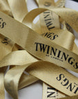 Gold metallic ribbon with "Twinings of London" printed, showcasing shimmer and elegance for packaging or décor.