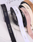 Custom polyester cotton ribbon in various colors, featuring decorative text for gift wrapping and branding.