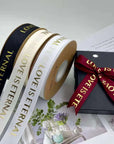 Custom grosgrain ribbon rolls in black, white, and red with "LOVE IS ETERNAL" text, perfect for packaging and crafts.