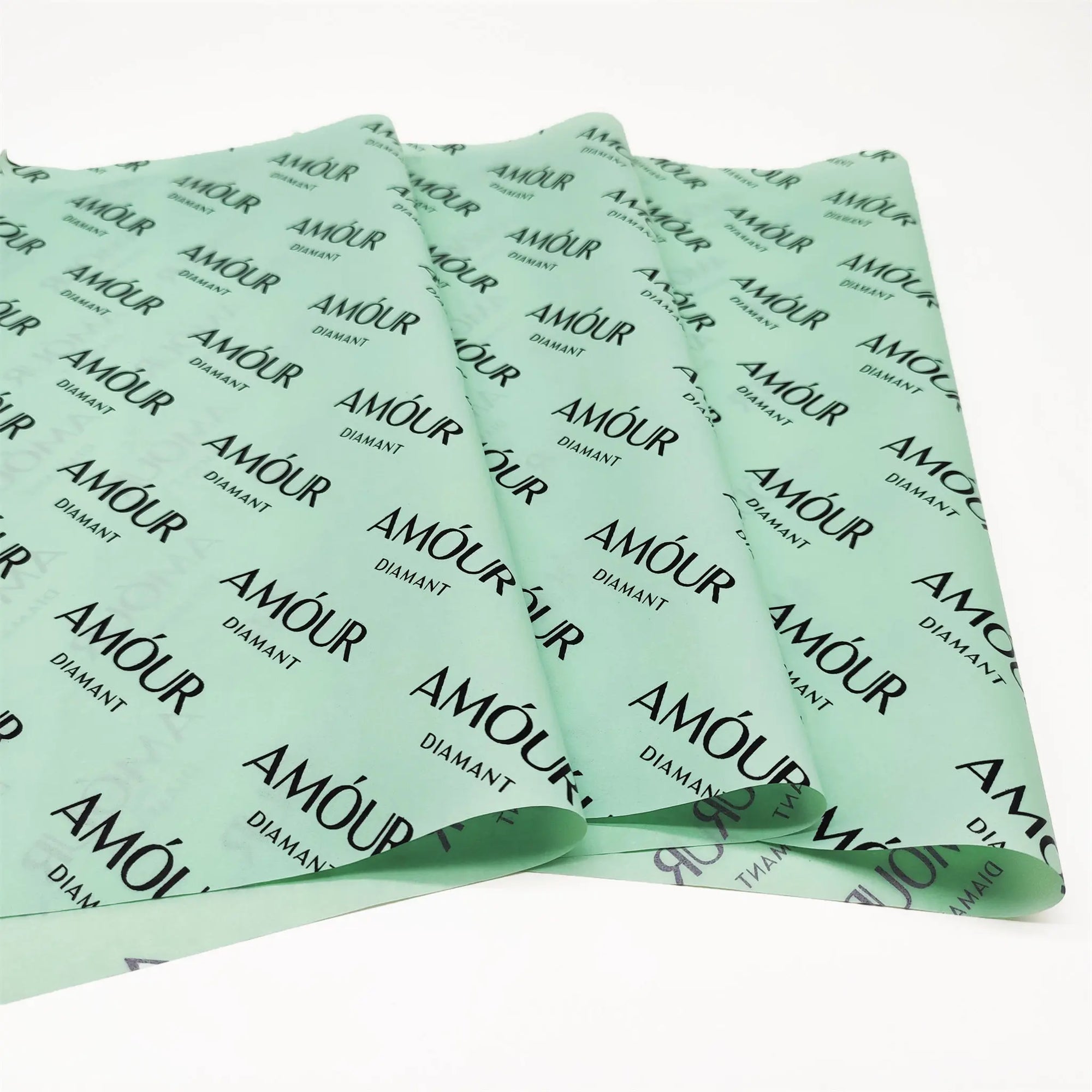 Custom tissue paper in mint green featuring &quot;AMOUR&quot; branding for elegant packaging and enhanced unboxing experience.