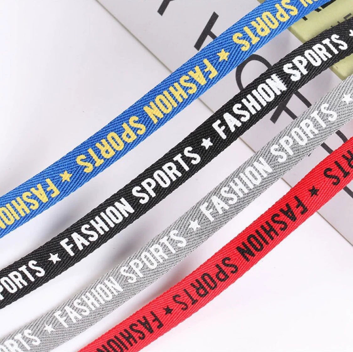 Custom herringbone ribbons in blue, black, gray, and red labeled 'FASHION SPORTS' for stylish packaging and crafts.