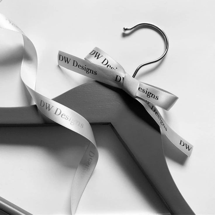 Custom satin ribbon tied on a hanger with DW Designs logo, showcasing elegance for gifts or event presentations.