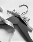 Custom satin ribbon tied on a hanger with DW Designs logo, showcasing elegance for gifts or event presentations.