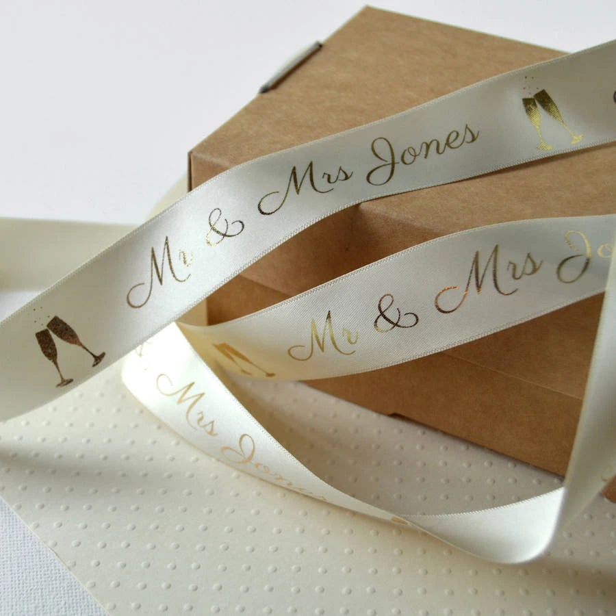 Custom satin ribbon with "Mr & Mrs Jones" and champagne glasses design on a gift box.