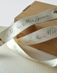 Custom satin ribbon with "Mr & Mrs Jones" and champagne glasses design on a gift box.