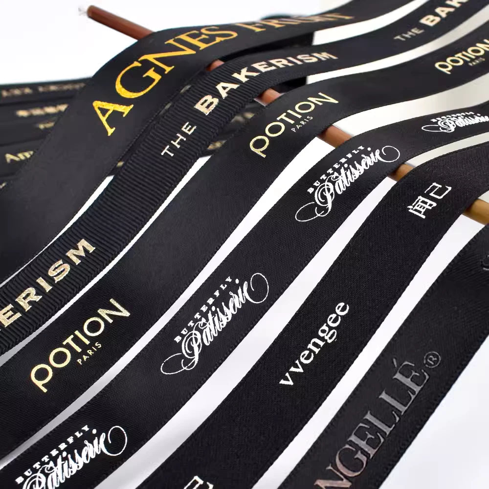 Custom grosgrain ribbon featuring various logos in black and white, showcasing its stylish and durable design.