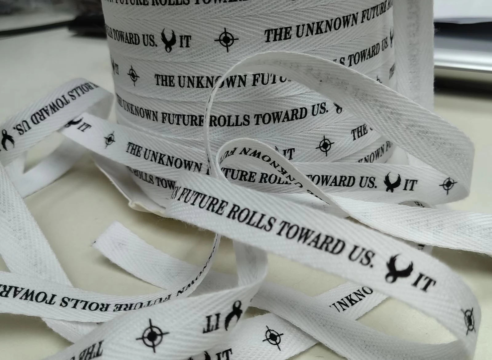 Custom herringbone ribbon featuring the phrase "The Unknown Future Rolls Toward Us" in black on a white background.