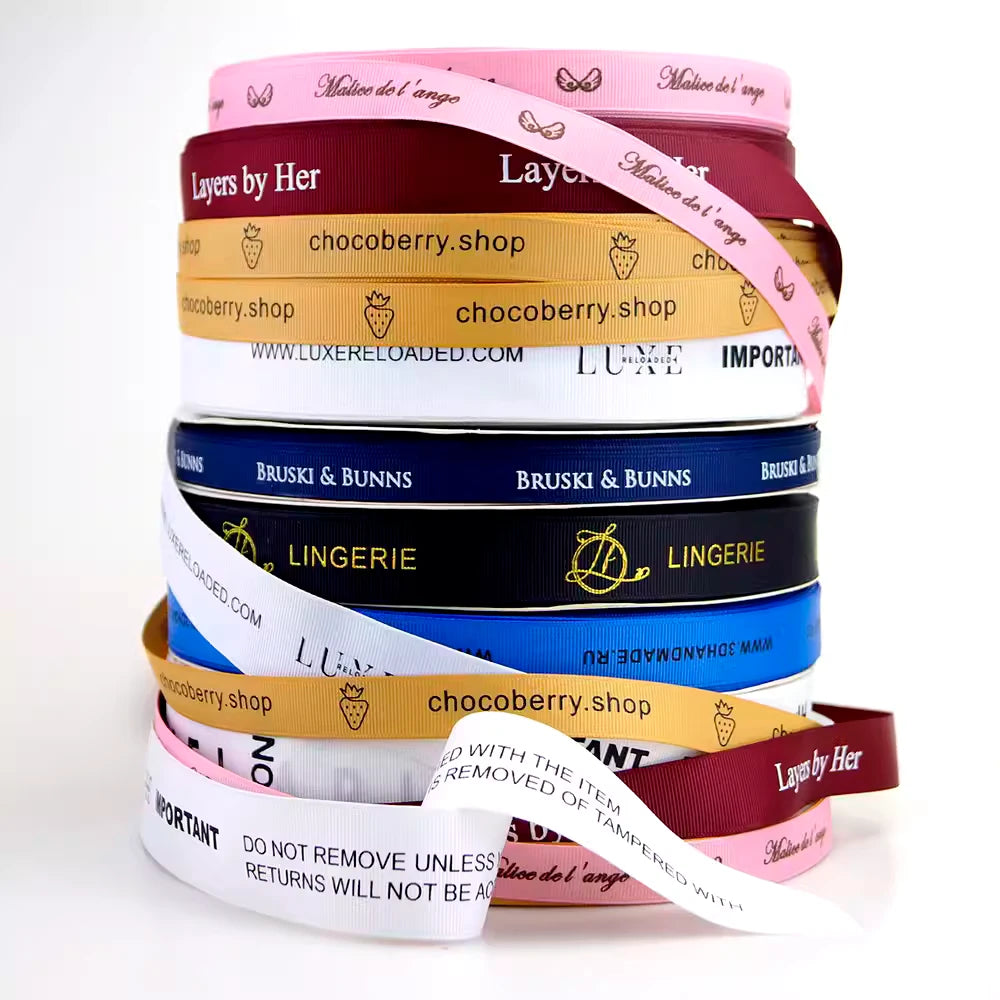 Stack of colorful custom grosgrain ribbons featuring various logos and text, ideal for crafting and branding.