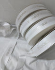 Custom satin ribbon rolls with embossed "TASOKO" logo, featuring a soft, luxurious finish. Perfect for gifts and decorations.