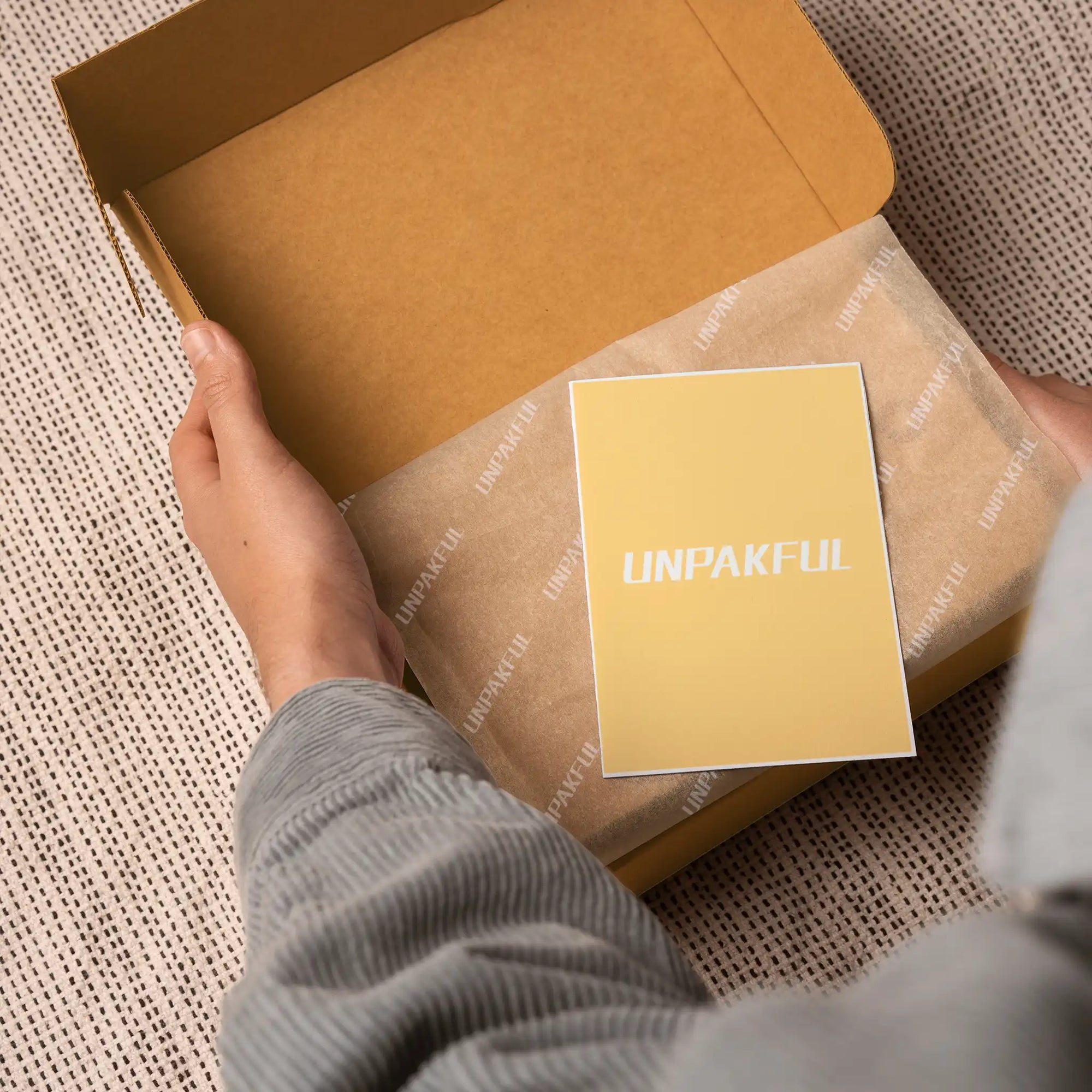 Person holding a custom branded card inside a stylish packaging box, showcasing a memorable unboxing experience.